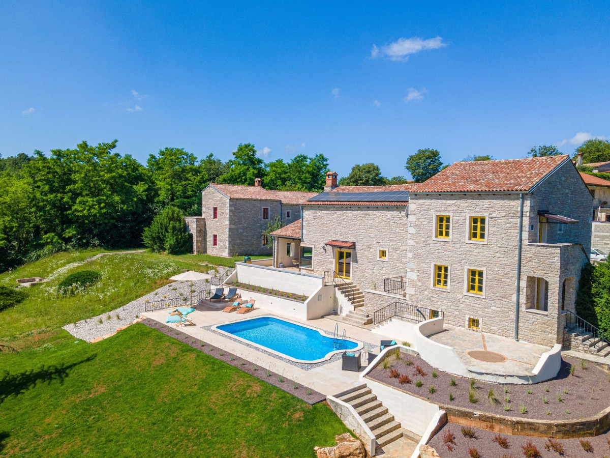 Restored stone villa with yellow shutters and a pool on a green hillside, Villa Di Kyra near Pazin, Istria