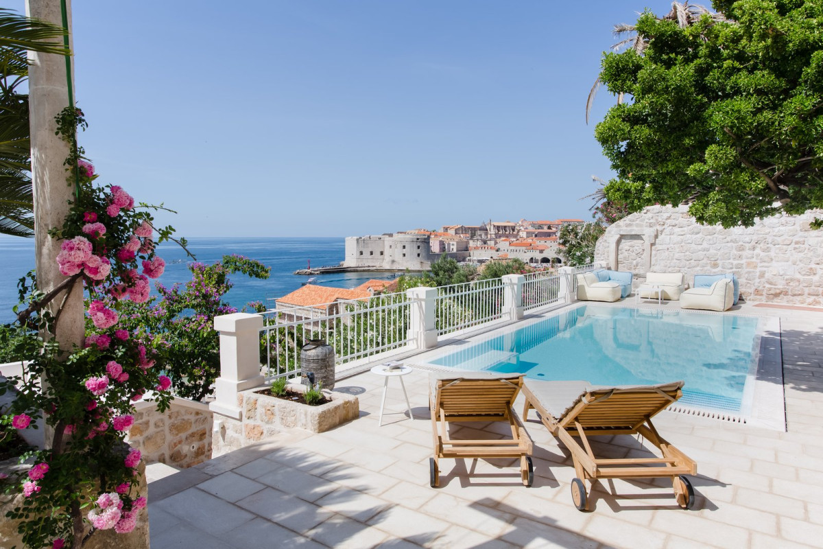 Pool terrace with sun loungers and roses, with Dubrovnik's old town walls behind, Villa Beba